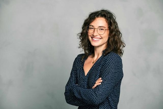 A woman smiles with arms crossed